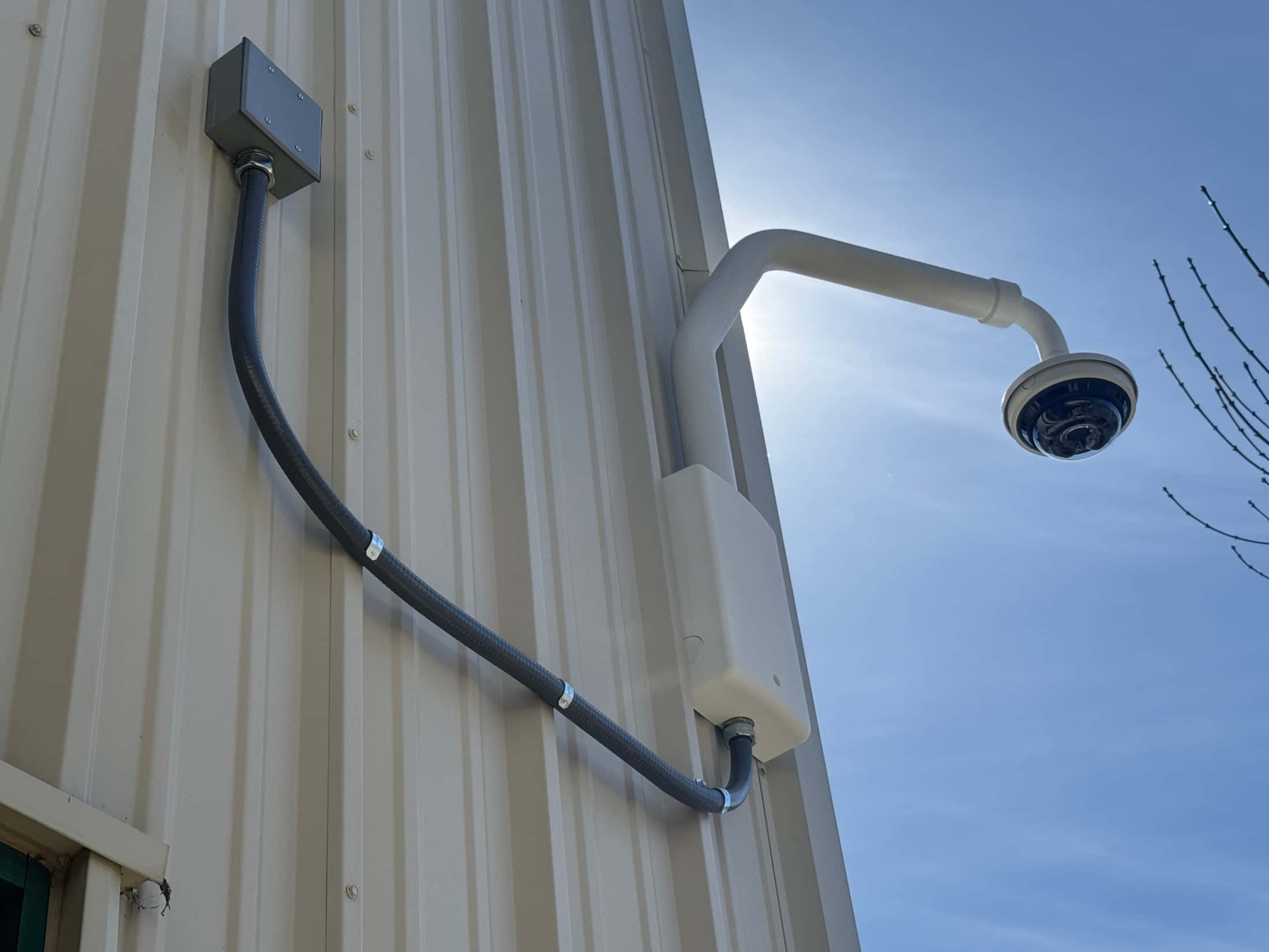 Exterior commercial security camera with conduit and a wall-mounted junction box